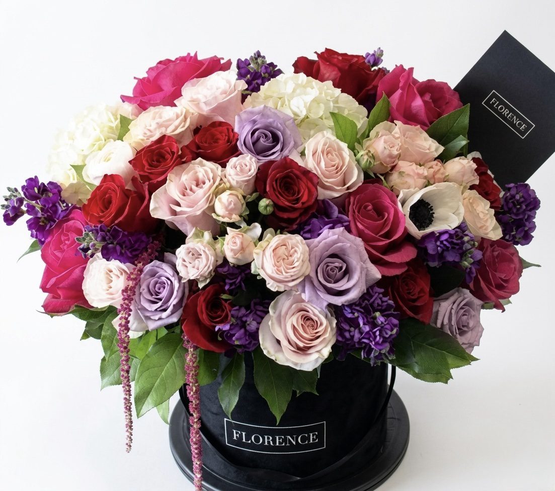 The All About Your Heart - Flower Box features red, pink, lavender, and white roses with purple blooms and greenery in a black hat box with a FLORENCE card—an elegant choice from Orange County Flowers.