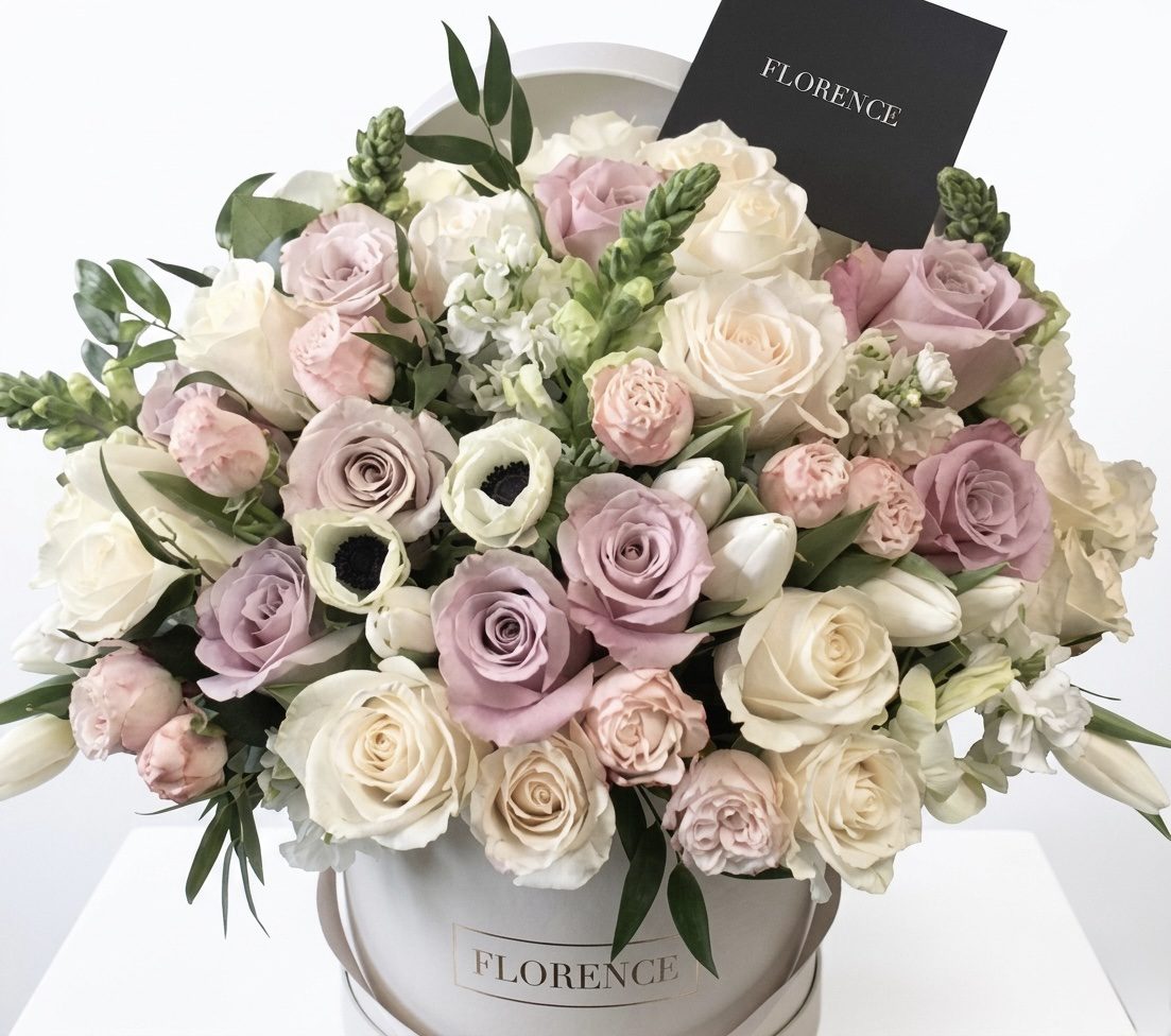 The FLEUR Collection #126 features a round white box filled with assorted pastel roses and flowers in white, pink, and lavender shades, green leaves, and a black FLORENCE card—a signature Orange County Flowers arrangement.
