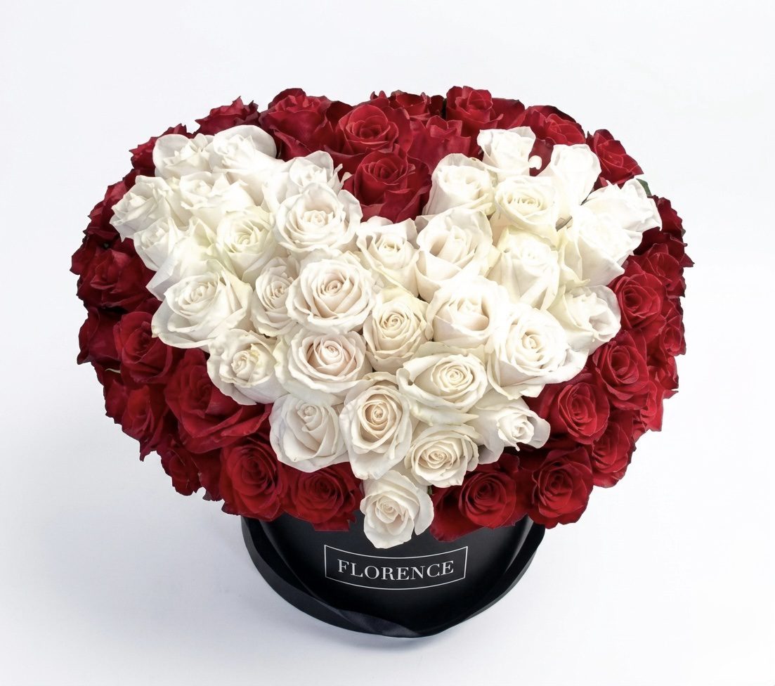 The Sexy Love - Flower Box features red roses arranged in a circle with white roses forming a heart in the center, all presented in a round black hatbox labeled FLORENCE by Orange County Flowers, shown against a plain white background.