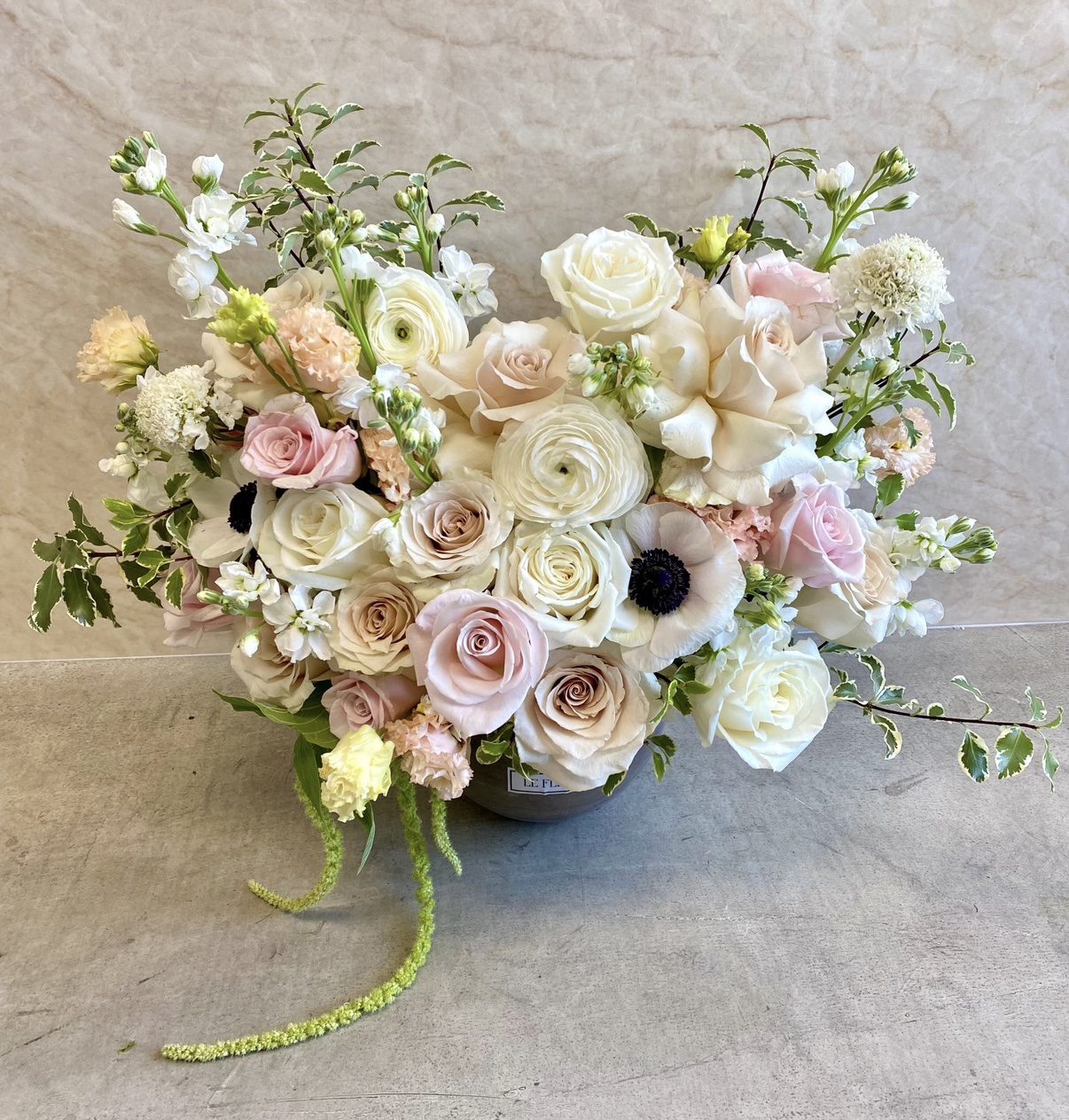 The Soft Girl Era - Ceramic Pot features a flower arrangement with white, cream, and pale pink roses, ranunculus, anemones, and delicate greenery in a vase against a light beige background.