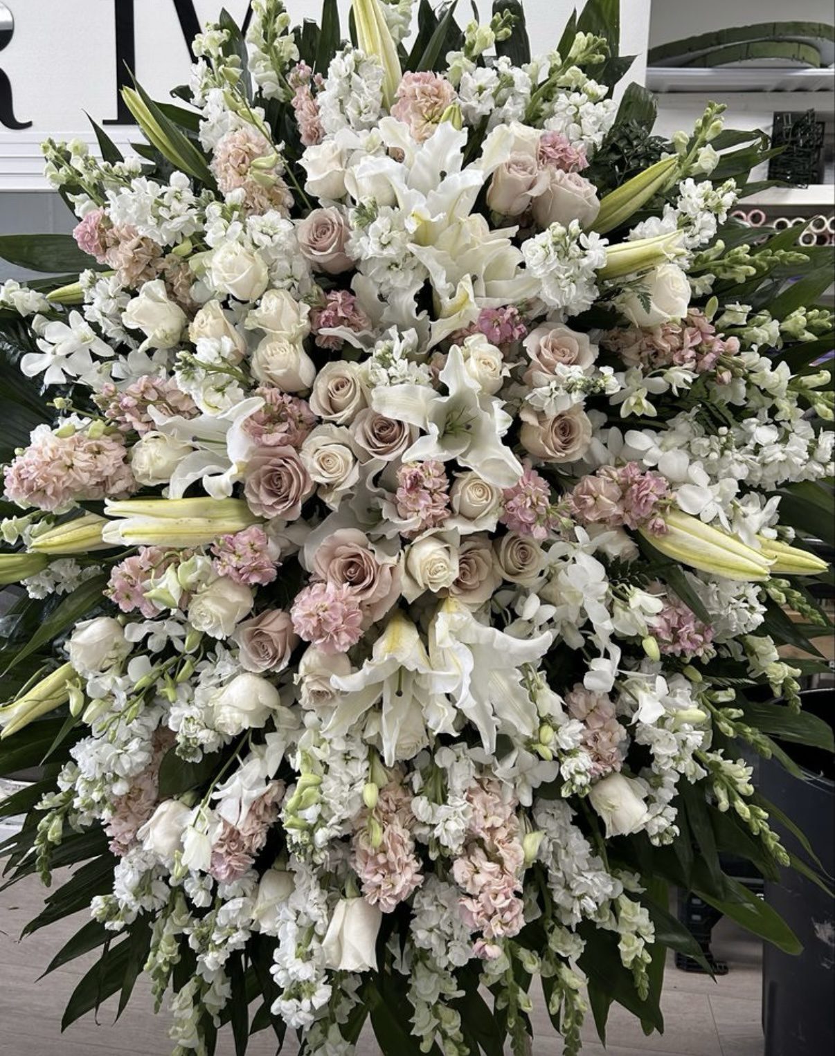 The Velvet Garden - Funeral Spray is a large, lush arrangement of white lilies, white and blush pink roses, and delicate greenery in a full, rounded shape.
